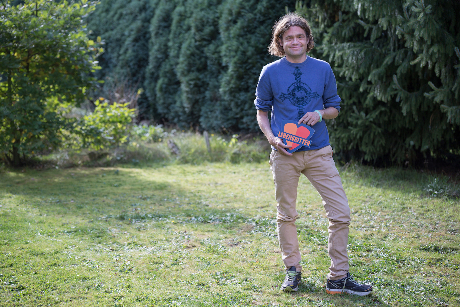 Dr. Fabian Kreutzer mit Lebensritterlogo in seinem Garten.